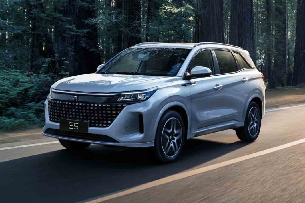 Vista frontal y lateral del SUV DFSK E5, color gris plateado, estacionado en una calle.